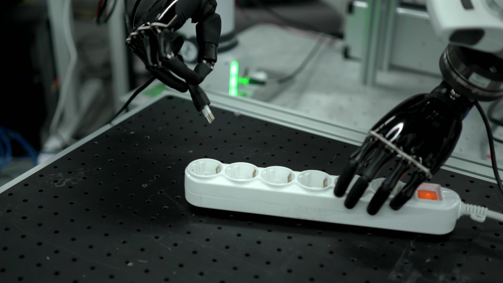 Real footage of a robot hand about to insert a plug into a power strip.